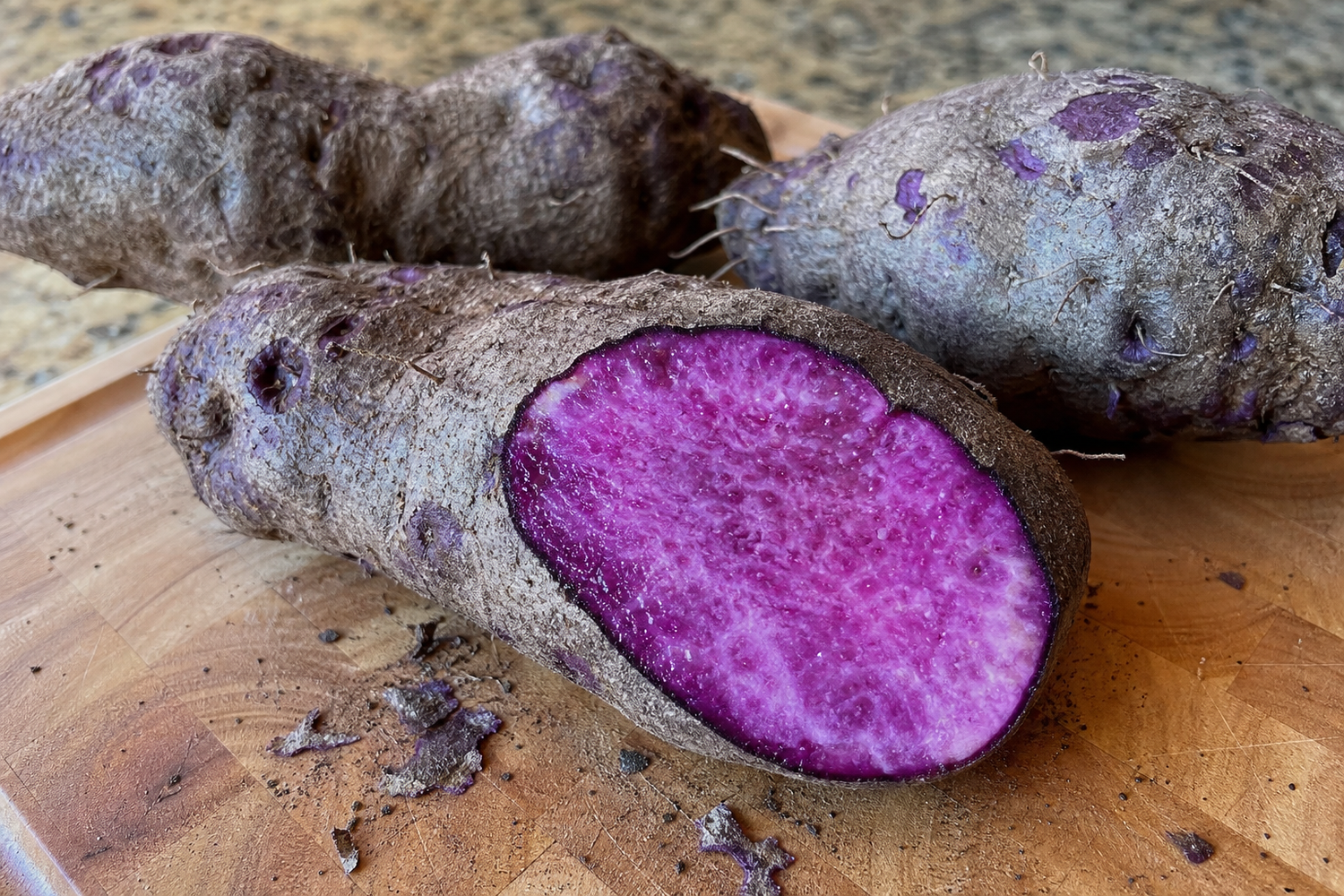 Real ube purple yam cut open on a wooden cutting board